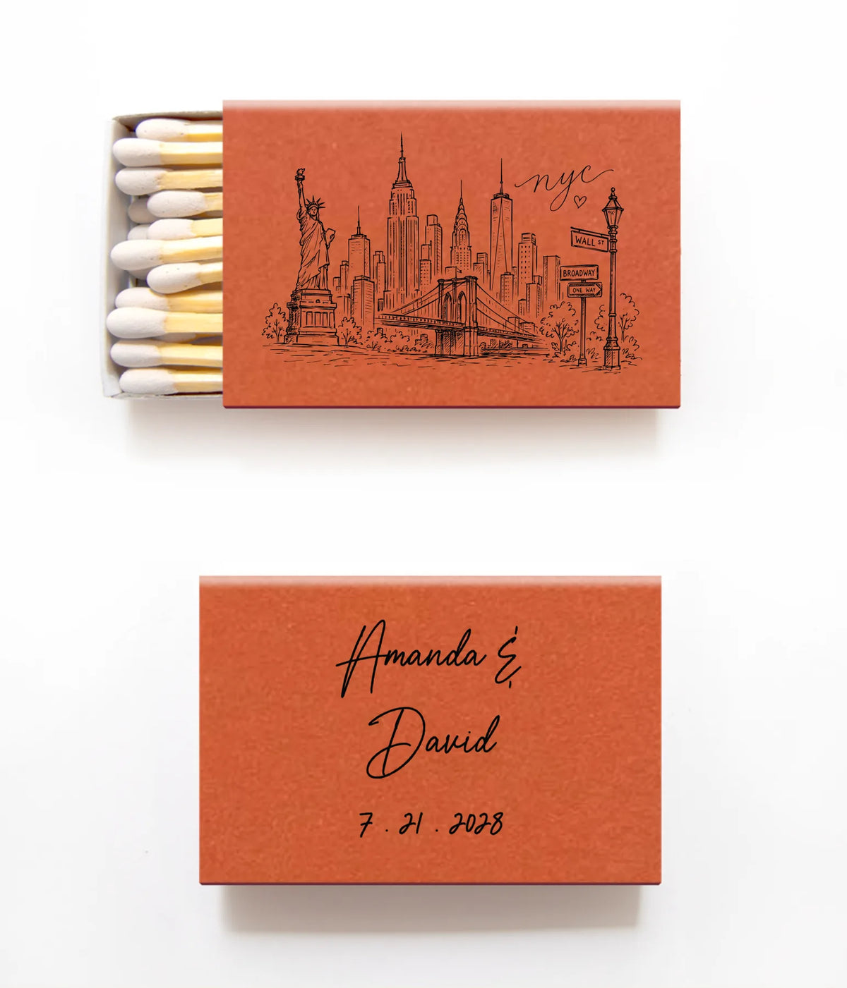 Personalized matchboxes on a white background, one showing the open interior with white matches and a black New York City skyline illustration, and the other closed with the names 'Amanda & David' and the date '7.21.