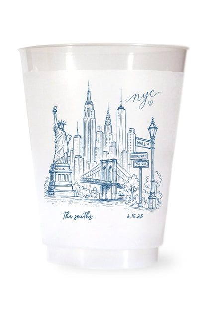 white shatterproof plastic cup on a white background. the cup is printed with a hand drawn illustration of the new york city sklyine with the bride and grooms names and wedding date in blue ink.