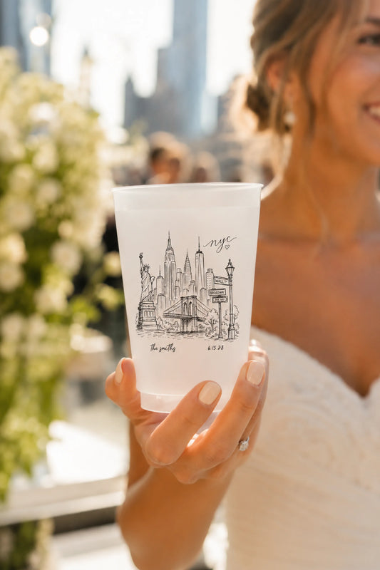 bride holding white cups with the new york city skyline on the cups in black.