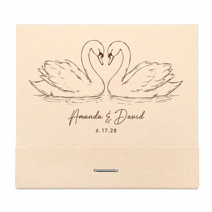 Beige matchbooks with line drawing of two swans and personalized text on a white background
