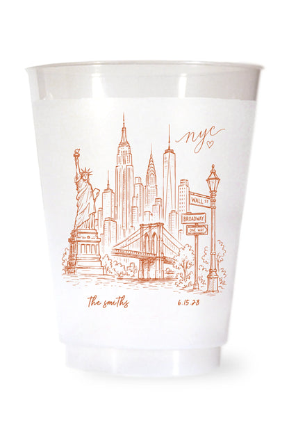 white shatterproof plastic cup on a white background. the cup is printed with a hand drawn illustration of the new york city sklyine with the bride and grooms names and wedding date in terracotta ink.