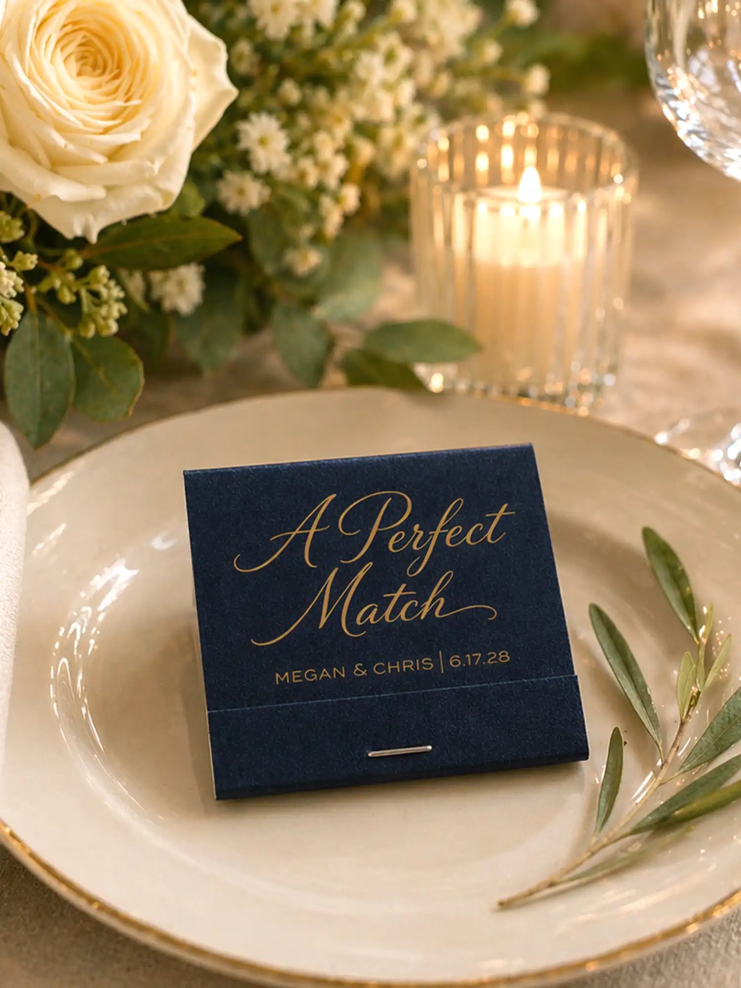 Navy blue 'A Perfect Match' card on a white plate with flowers and candles in the background