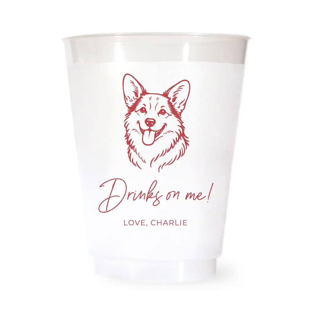 White cup with red corgi dog illustration and text 'Drinks on me! Love, Charlie' on a white background