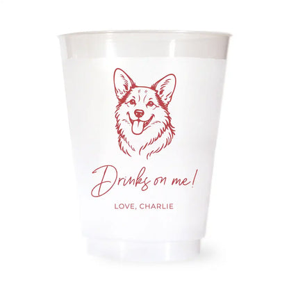 White cup with red corgi dog illustration and text 'Drinks on me! Love, Charlie' on a white background