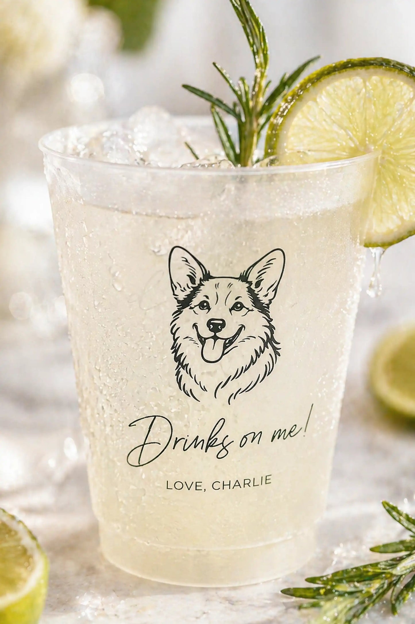 Cocktail in a clear glass with a corgi dog illustration and text, garnished with lime and rosemary.