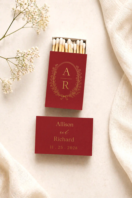 Red matchbox with 'AR' design and a personalized card on a soft fabric background.