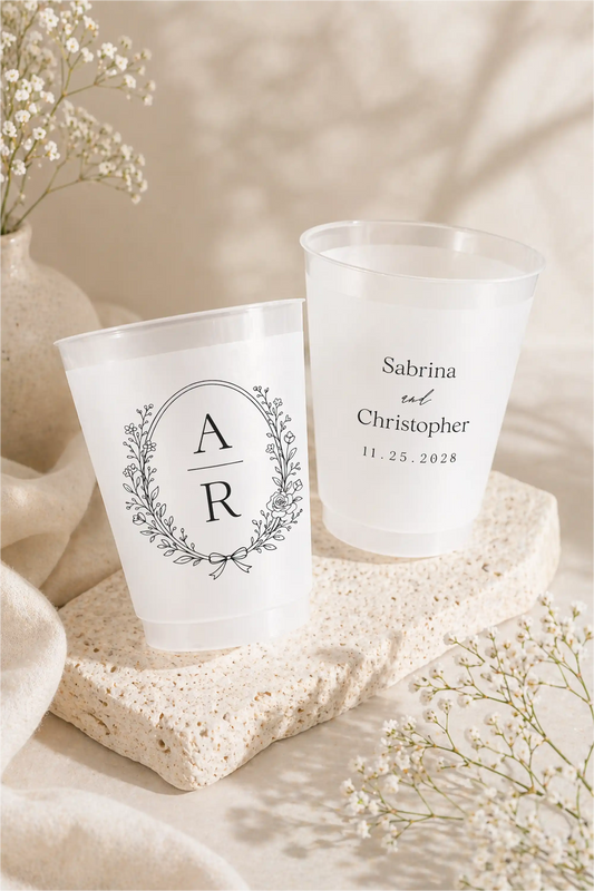 Two personalized frosted cups with monogram and names on a soft beige background