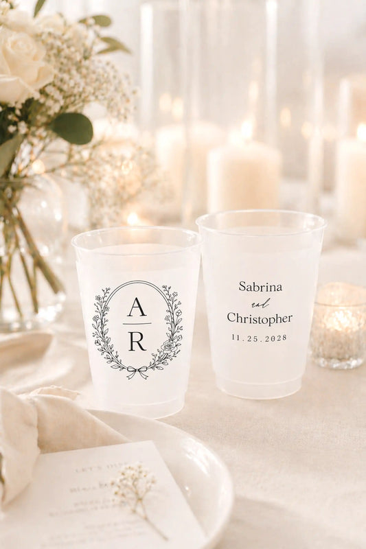 Two personalized candles with monogram and names on a decorative table with flowers and candles.