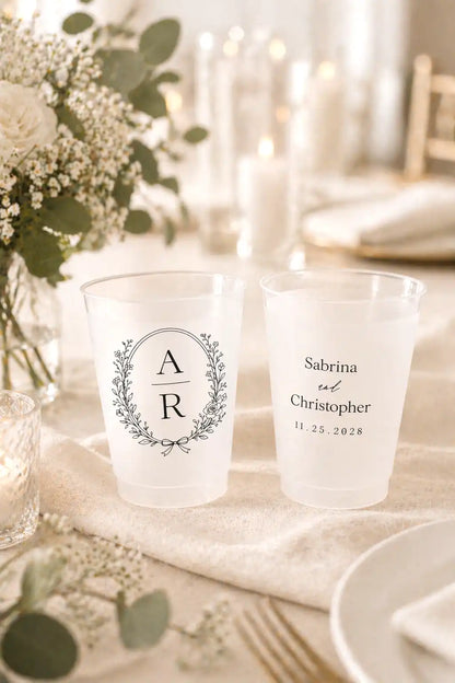 Two personalized frosted cups on a table with floral decorations
