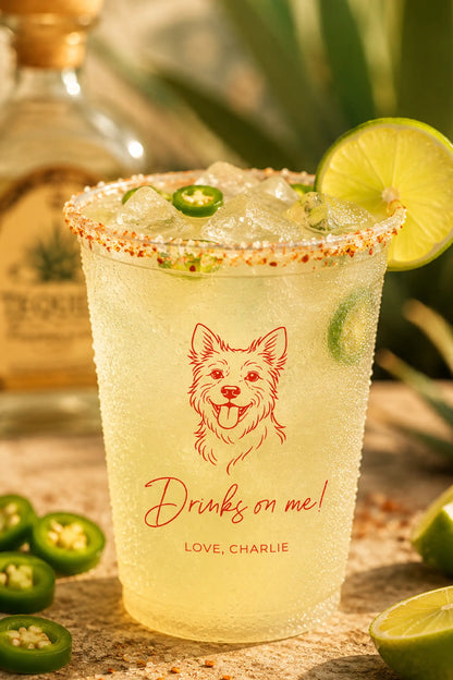 Glass of spicy margarita with a terrier dog illustration and 'Drinks on me! Love, Charlie' text, surrounded by limes and jalapeños.