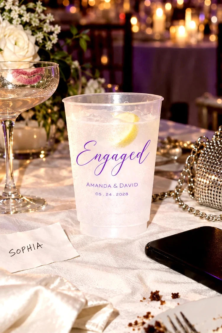 Personalized frosted engagement party cup with custom names and date at an elegant candlelit reception table