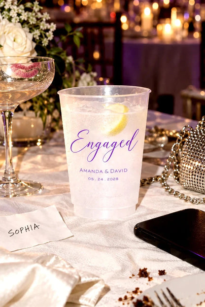Personalized frosted engagement party cup with custom names and date at an elegant candlelit reception table