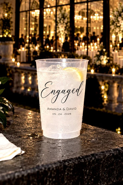 Personalized frosted engagement party cup with custom names and date at an elegant candlelit outdoor celebration