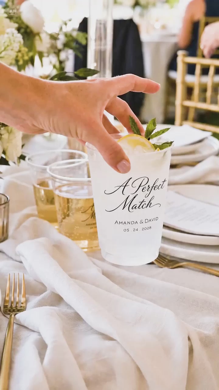 a hand placing on a white wedding table a cup that says a perfect match 