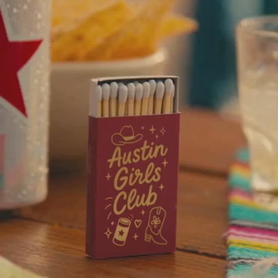 Austin girls club bachelorette party matches in red and gold on a party table with chips and drinks