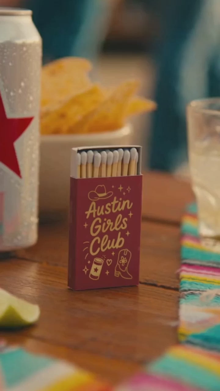 Austin girls club bachelorette party matches in red and gold on a party table with chips and drinks